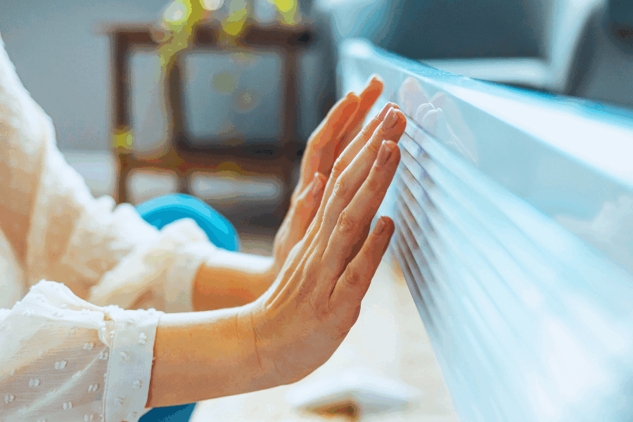 Cold hands and stiff joints holding up to heater for warmth