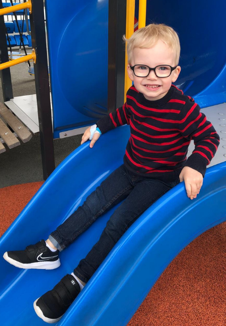 Child with wrist splint playing on slide after fracture treatment with Action Rehab